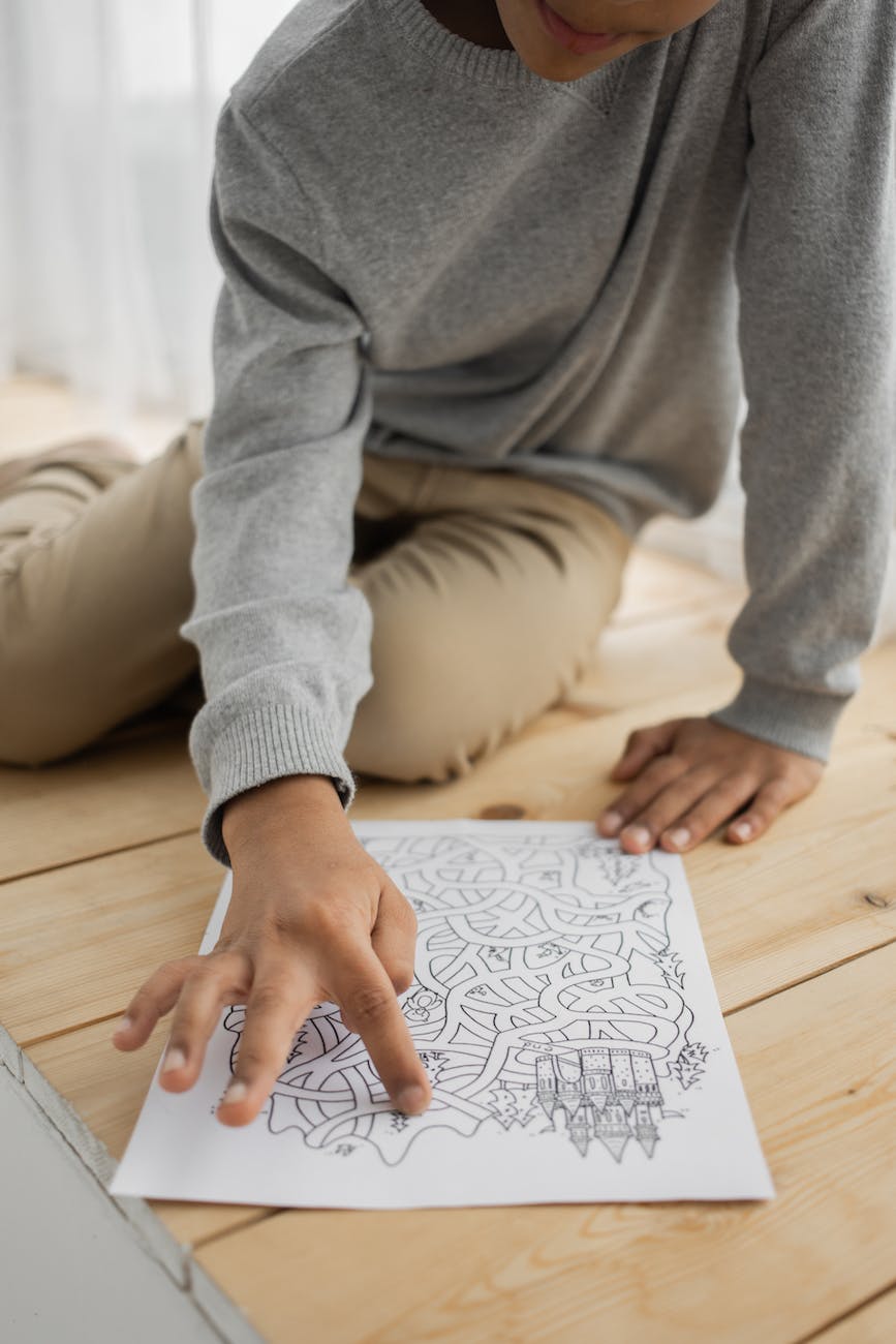 unrecognizable black child solving painted maze on floor at home